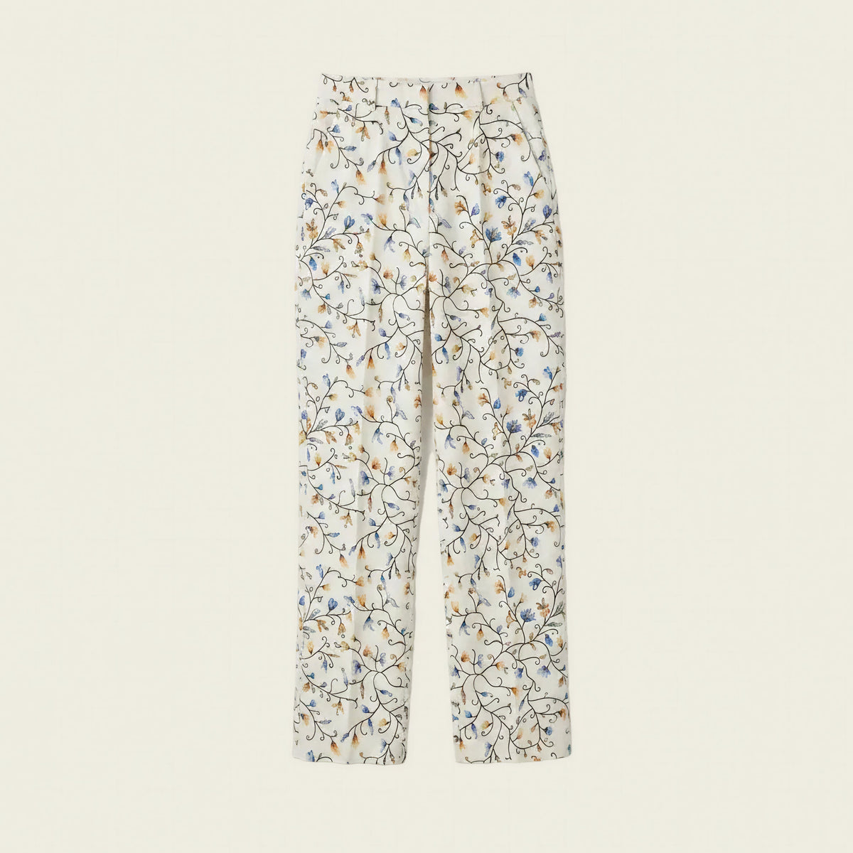 A pair of women's straight-leg trousers featuring an all-over delicate floral and branch print in blue, orange, and brown on a warm off-white background, shown flat against a solid cream backdrop.