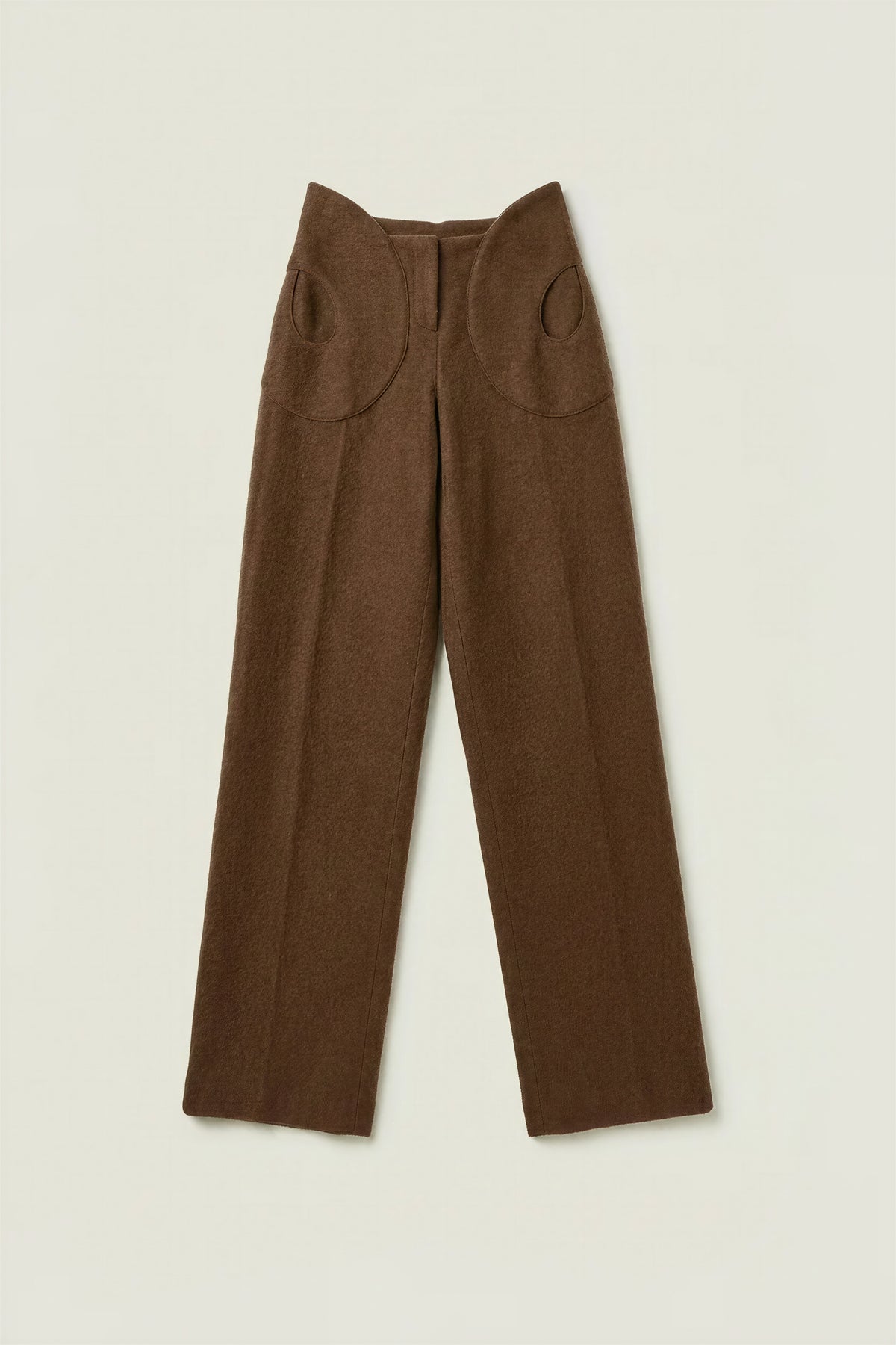 A pair of brown wide-leg trousers with unique circular cutout details on the upper thighs, laid flat against a light beige background.