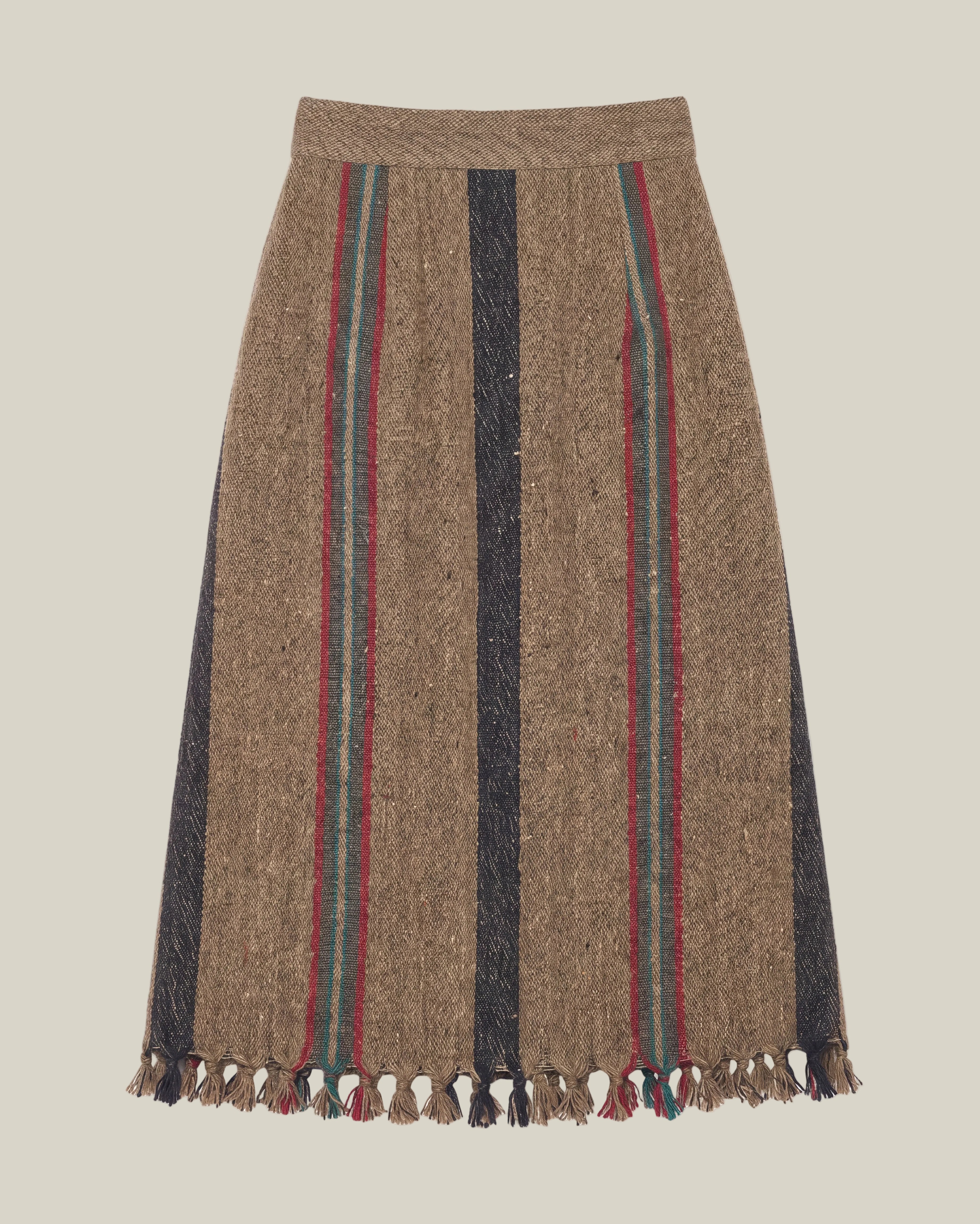 A brown wool skirt with vertical stripes in black, red, and green, finished with a fringed hem.