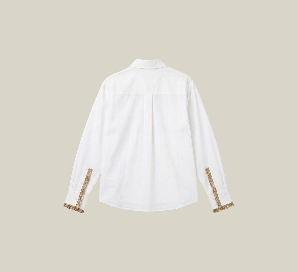 A white long-sleeve button-up shirt shown from the back, featuring decorative gold patterned cuffs, displayed on a clean white background with a beige border.