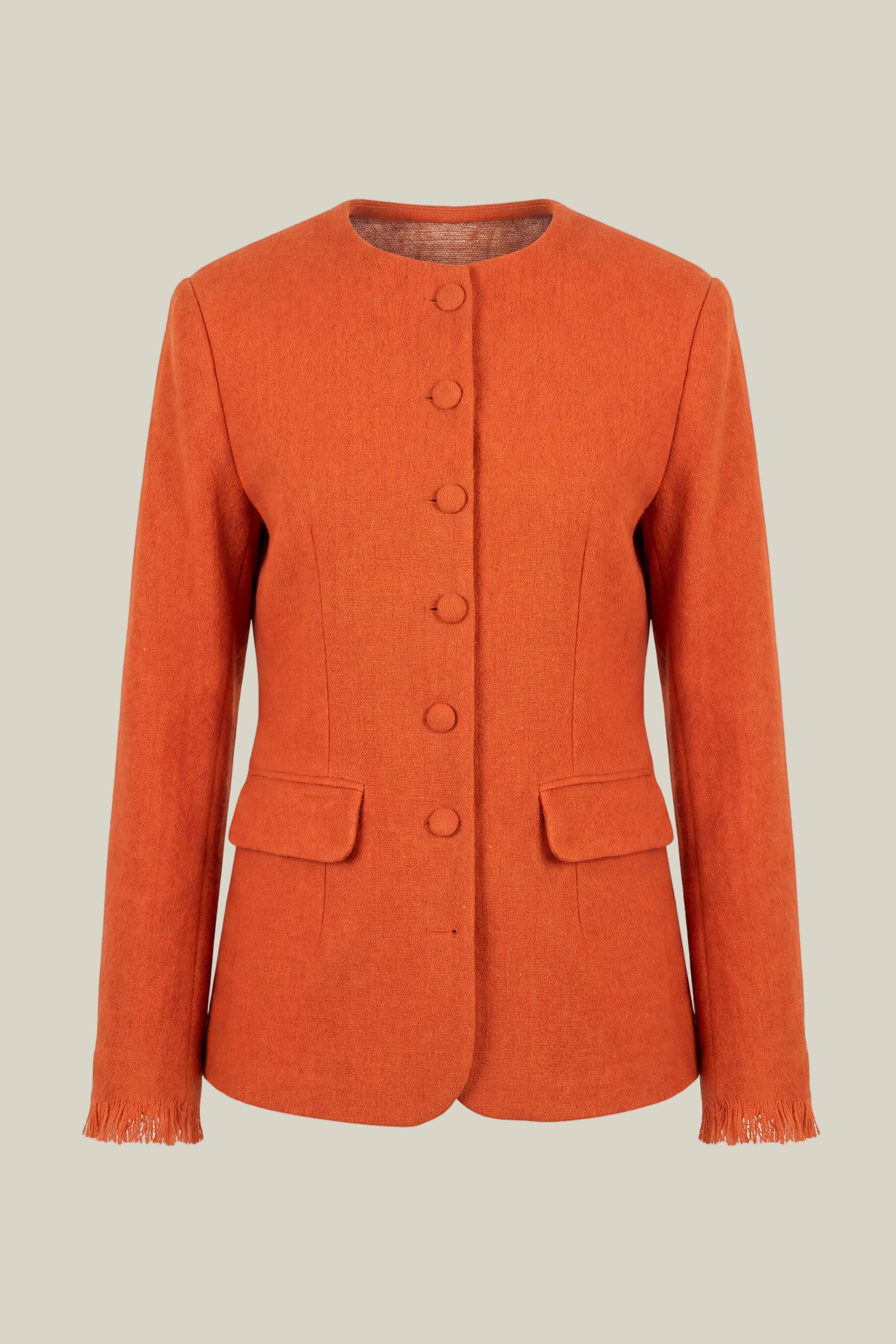 An orange textured handwoven  wool jacket with a round neckline, five front buttons, flap pockets, and fringed cuffs, shown against a plain white background.
